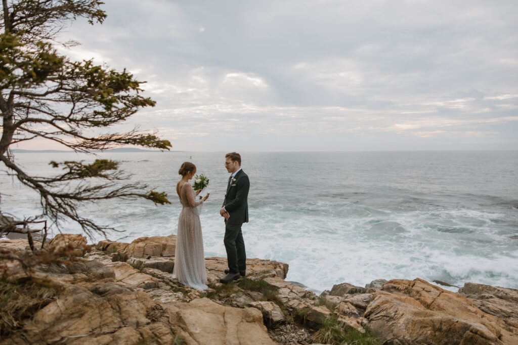 Couple standing on Otter cliffs reading vows