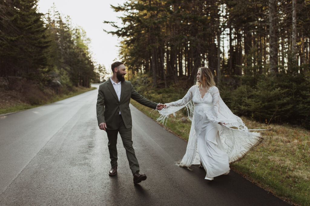 Couple holds hands while walking down Park loop road in Acadia 